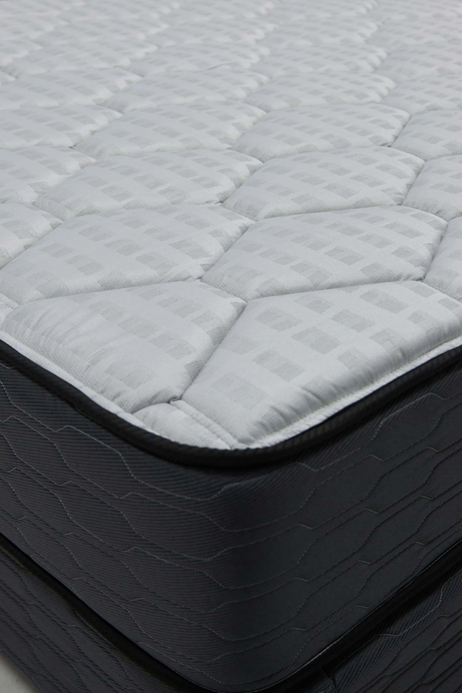 Close-up corner of a quilted grey and white mattress ready for collection