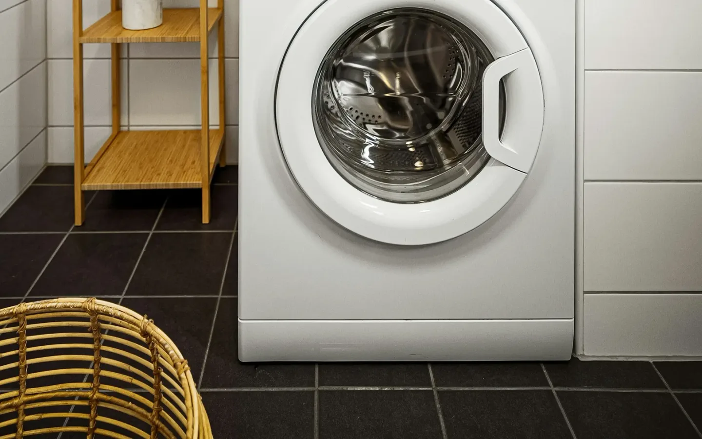 Freestanding washing machine in a tiled utility area with a clear route for removal