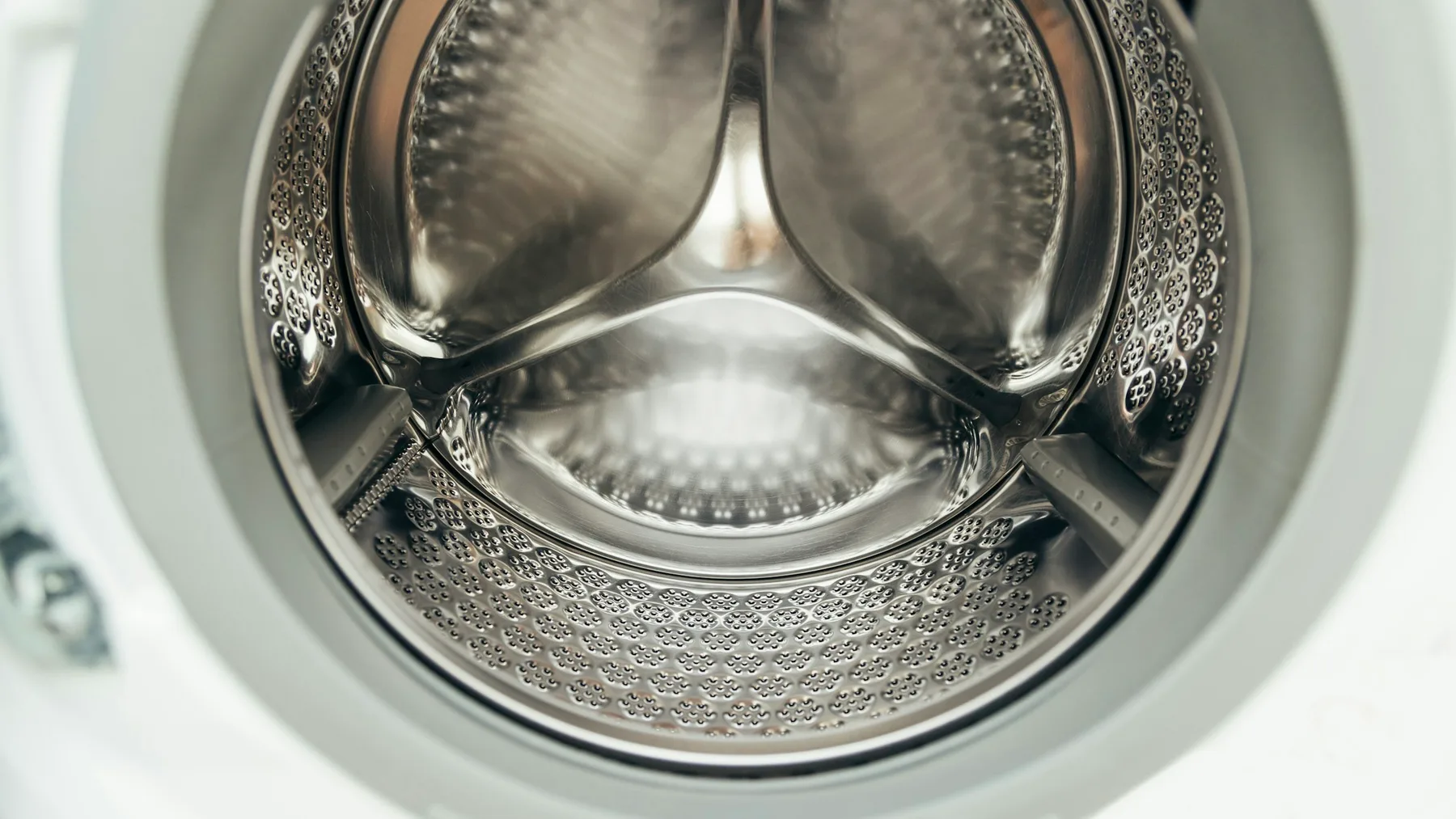 Close view inside the stainless steel drum of an empty front-loading washing machine