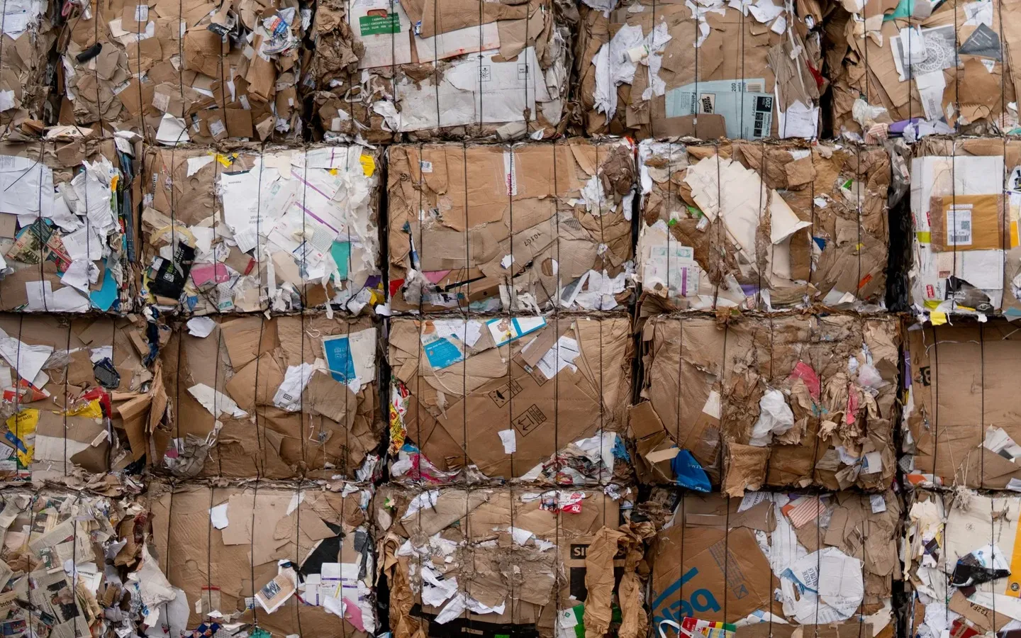 Compressed bales of mixed cardboard and paper stacked at a recycling yard after collection