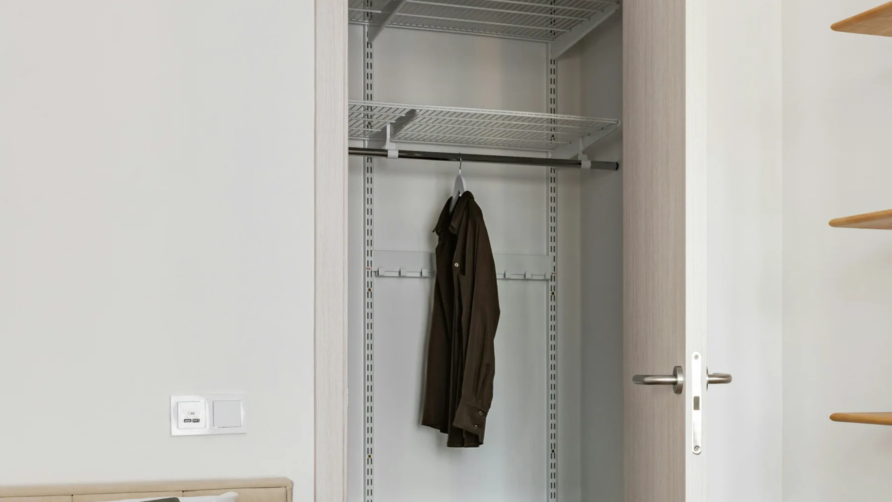 Open built-in wardrobe emptied down to a single jacket on a hanger in a bedroom