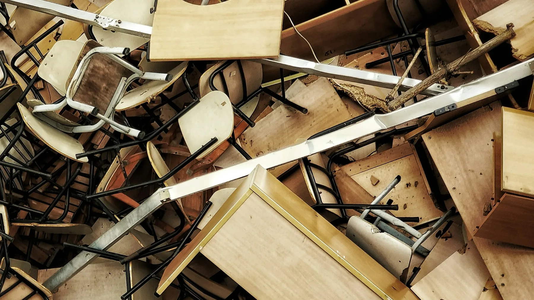 Overhead view of discarded chairs, plywood desk tops and cabinet panels heaped together after a clearance