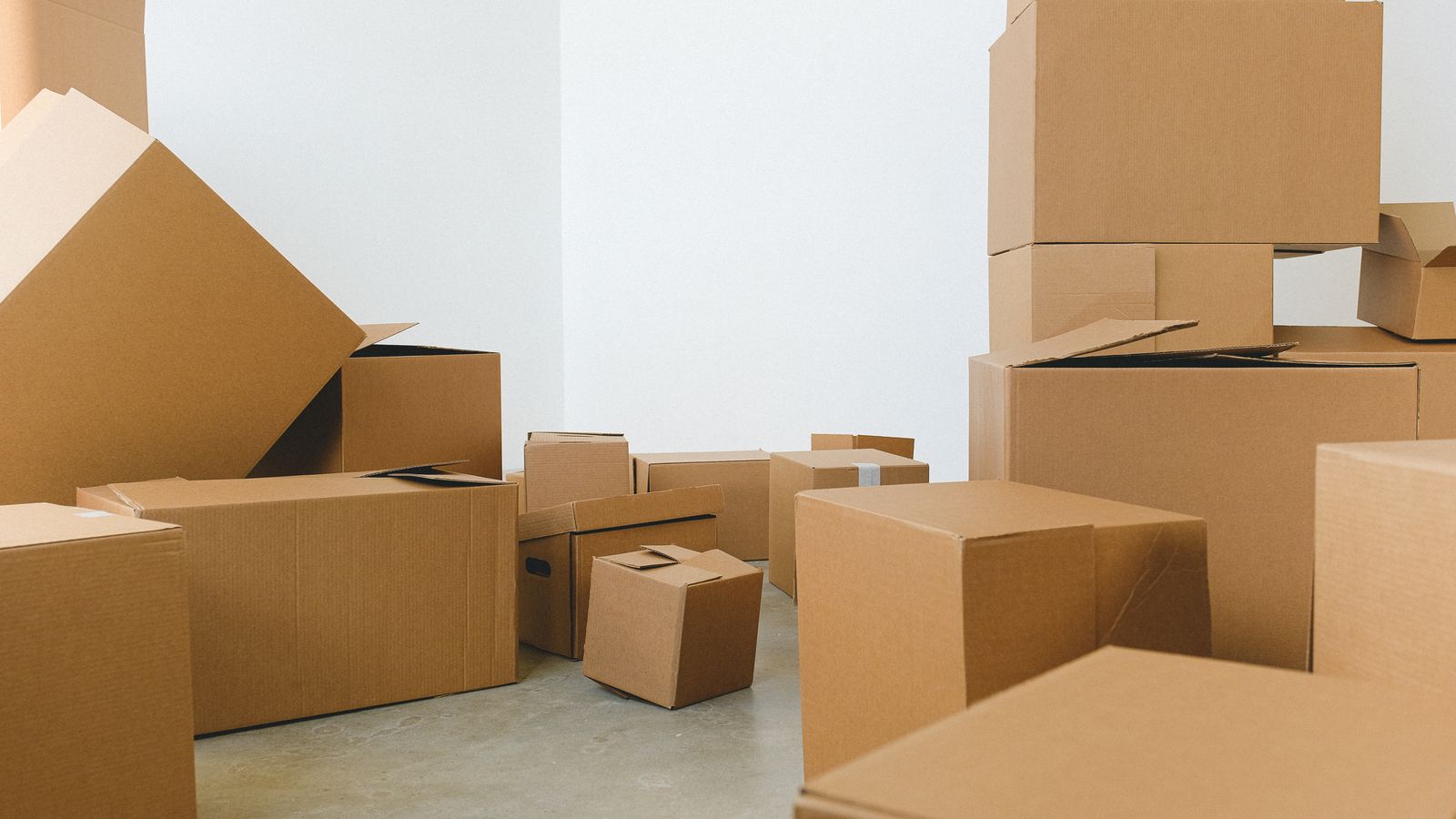 Assorted empty cardboard boxes of different sizes stacked across a bare room