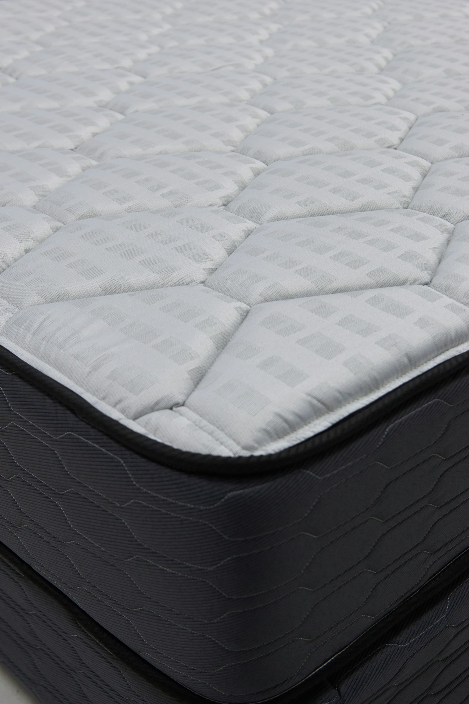 Close-up corner of a quilted grey and white mattress ready for collection