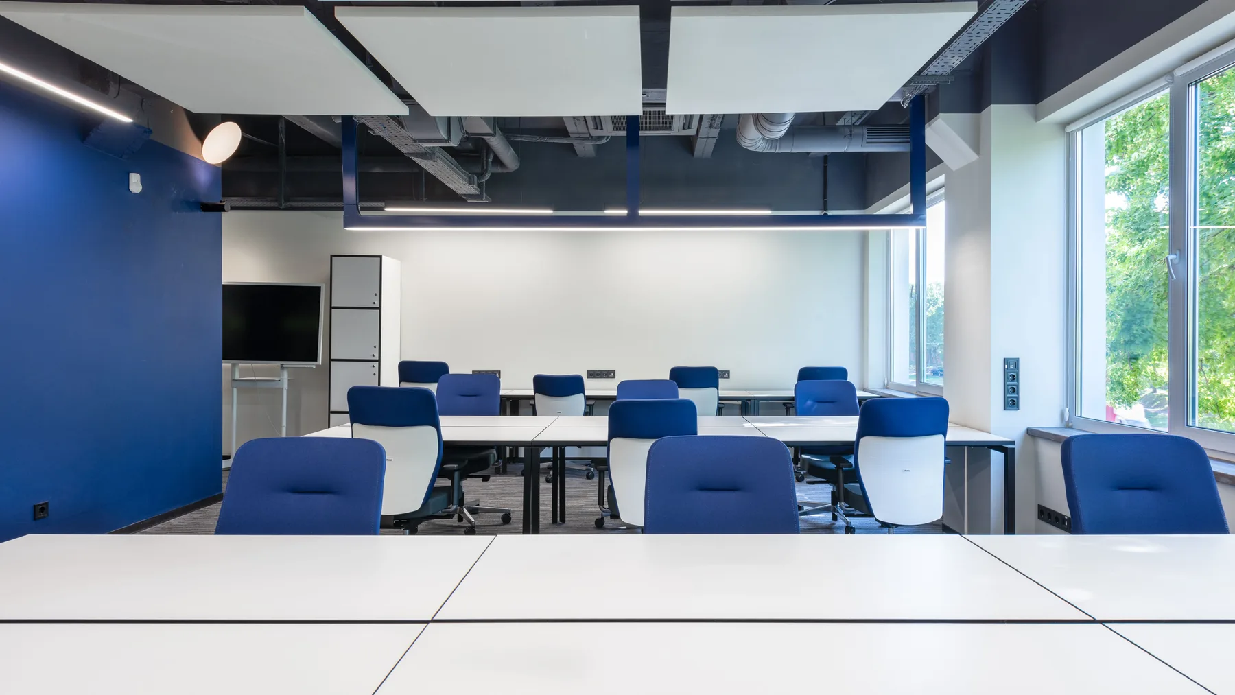 Spacious modern office and training room in Dubai with rows of white desks and blue task chairs