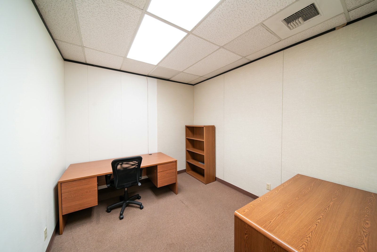 Empty office room with a desk, chair and bookshelf left behind ahead of clearance