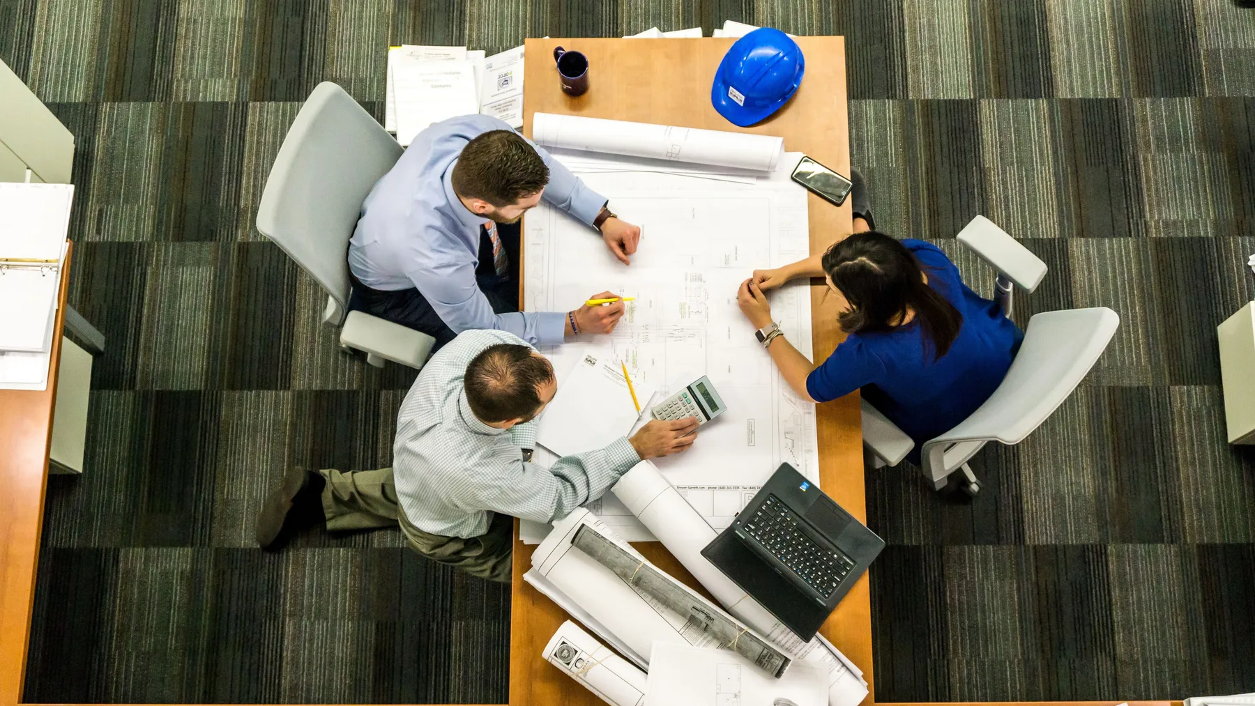 Facilities team reviewing architectural blueprints and workstation layout plans for commercial office junk removal in Dubai