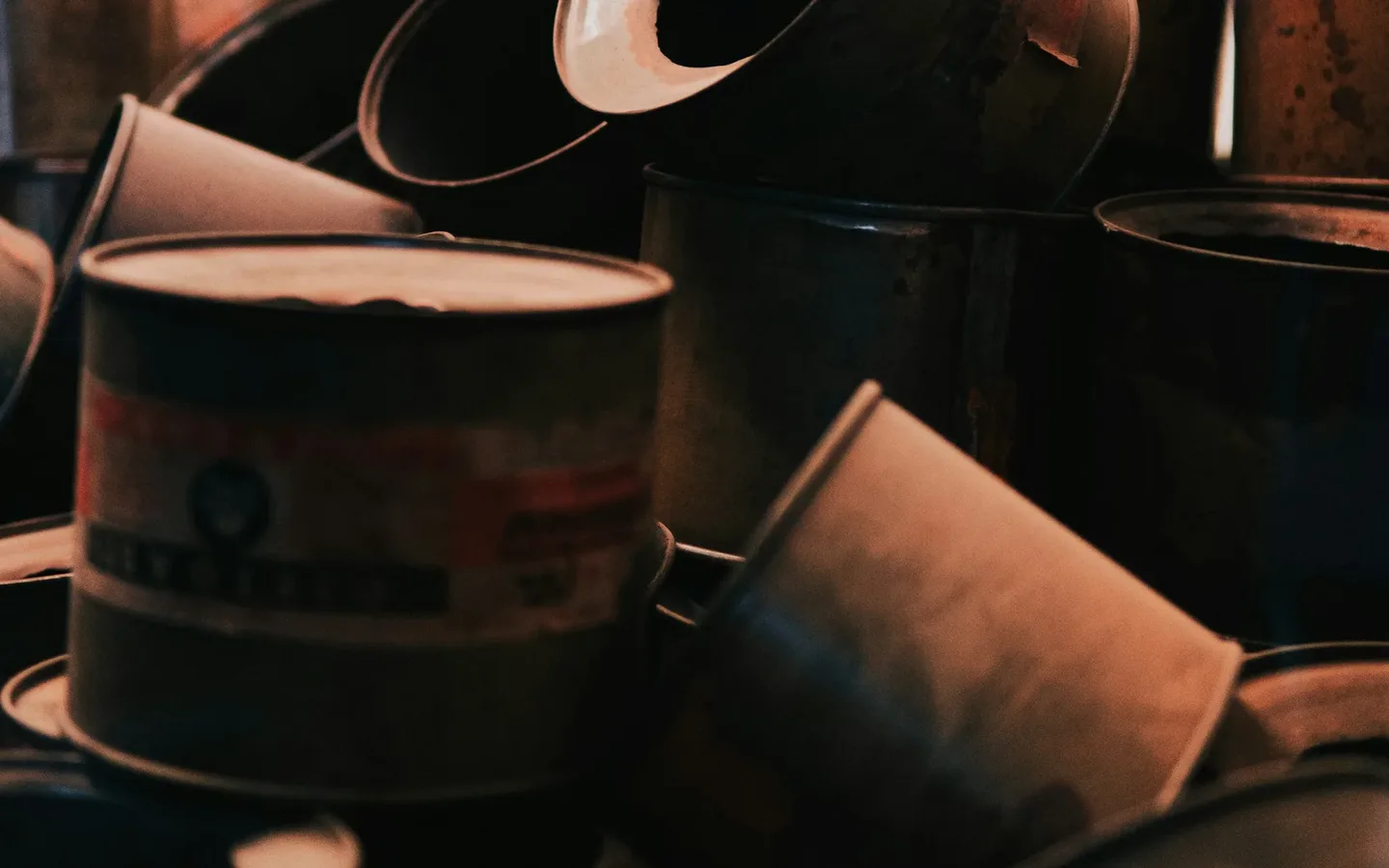 A collection of sealed paint cans and household maintenance supplies sorted on a utility shelf in a garage