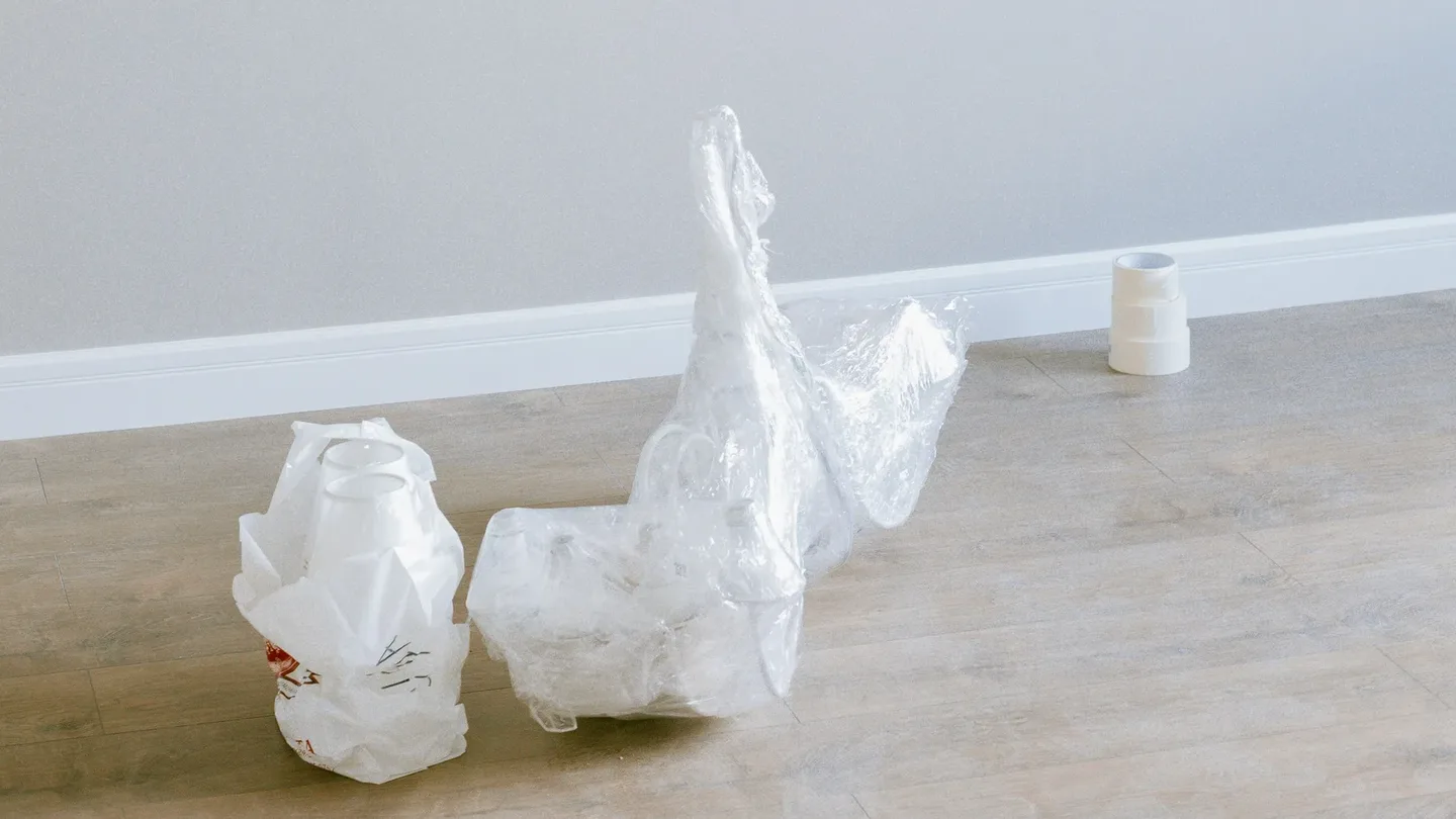 Rolls of protective film, discarded packaging boxes and masking tape on the tiled floor of a renovated Dubai apartment