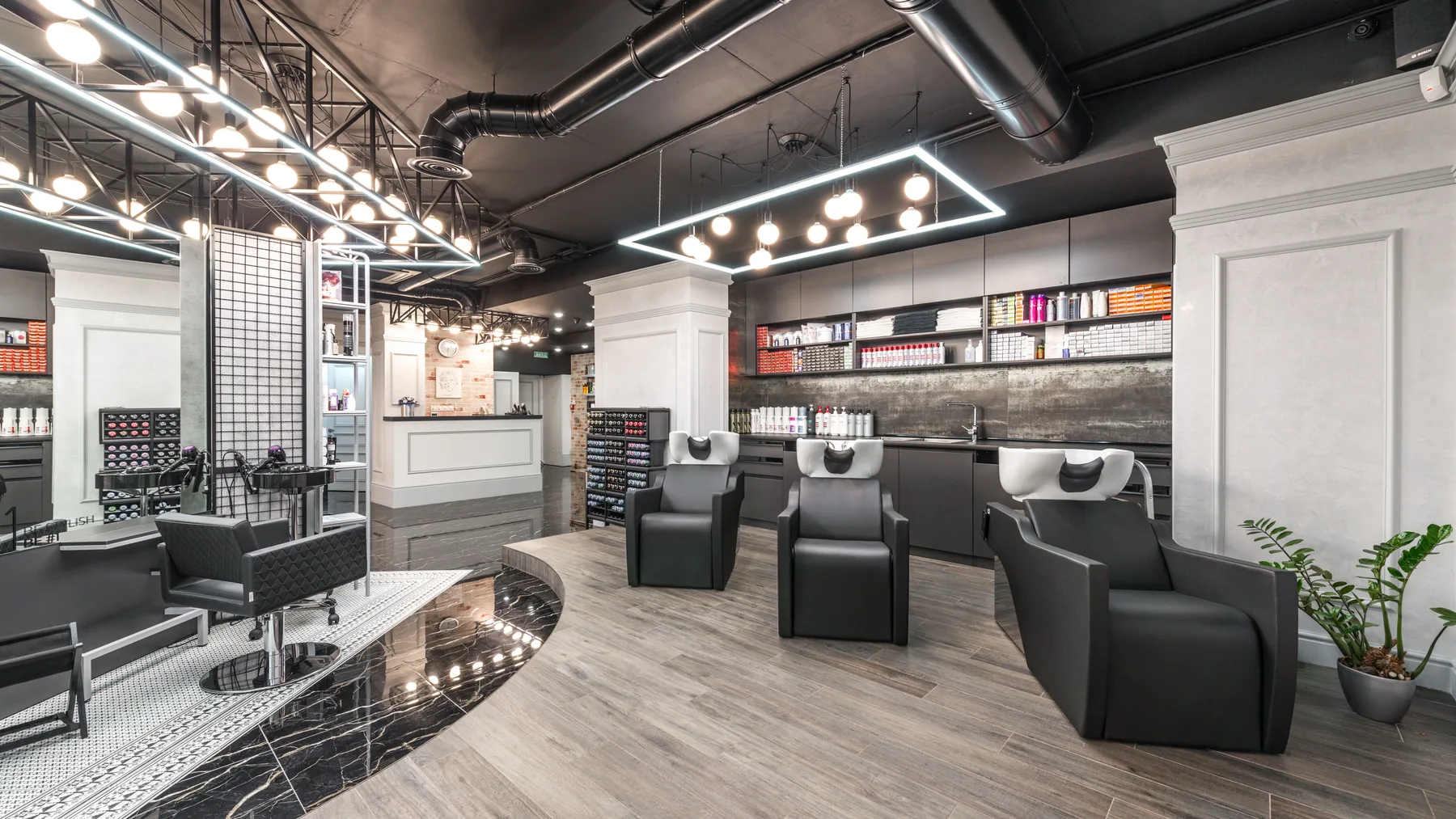 Modern beauty salon interior in Dubai with shampoo backwash basins, leather styling chairs, and mirrors