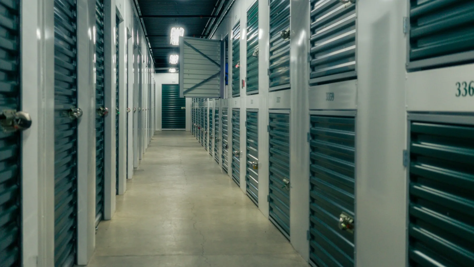 Corridor of self-storage unit doors with roller shutters and padlocks in a storage facility