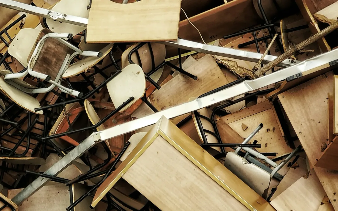 Mixed broken wooden furniture panels and metal frames grouped together for material sorting after damage