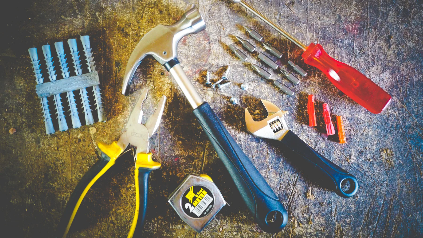 A workshop tabletop filled with assorted tools, hardware fixtures, and workshop equipment